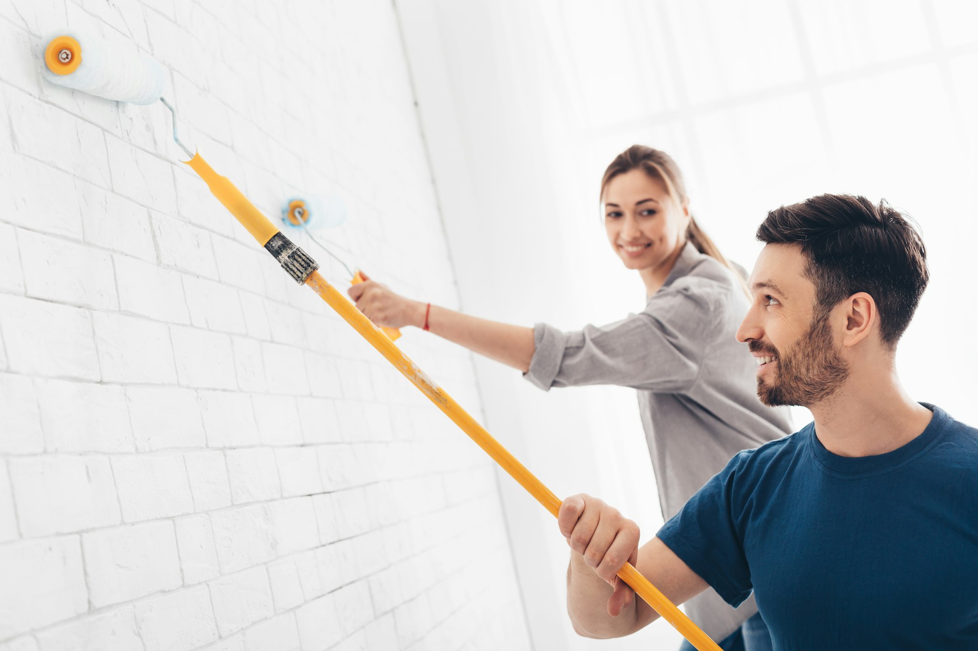 Happy couple painting walls at home, copy space