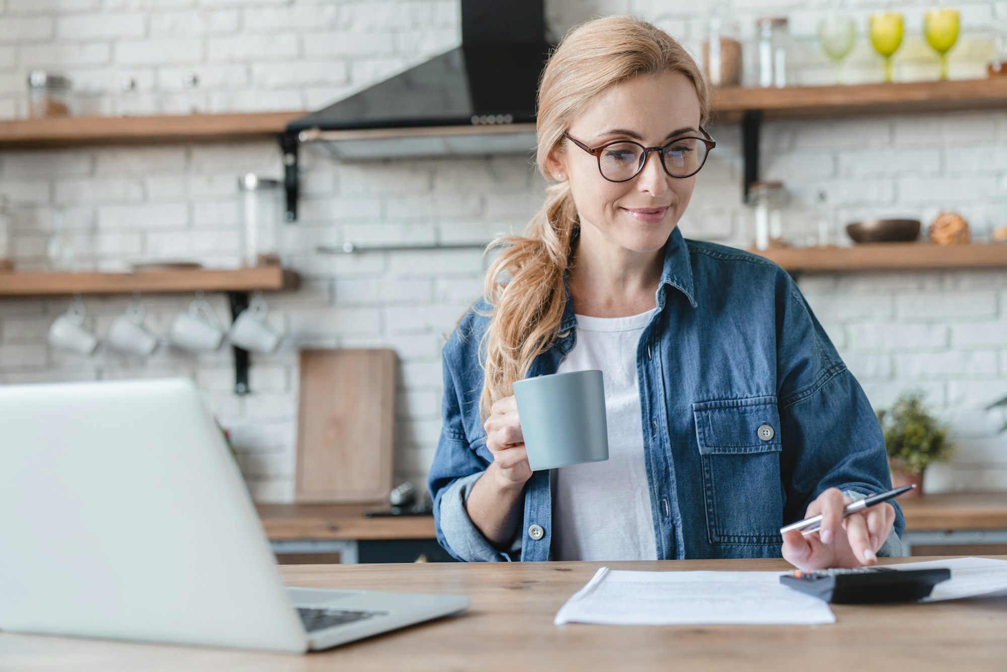 Paying bills,calculation on laptop at home. Mature woman counting money at home kitchen, mortgage