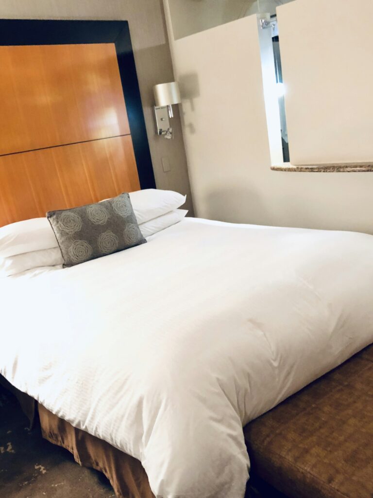 Hotel room bed with white bedspread.